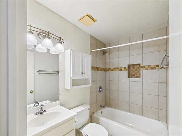 a bathroom with a bathtub shower sink vanity and toilet