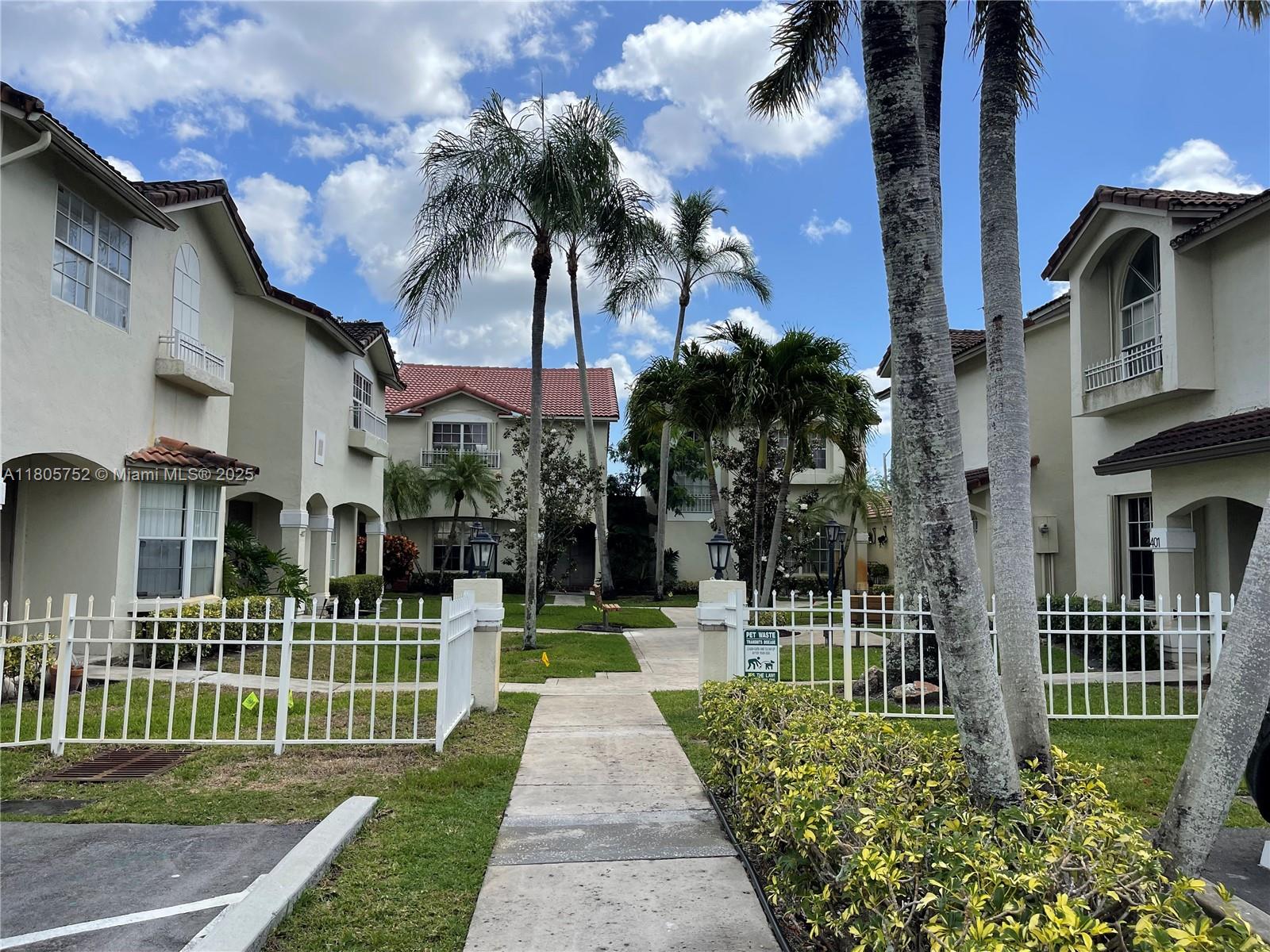 805 Northwest 108th Terrace, Unit 7L5 Pembroke Pines, FL 33026 - Photo 3 of 28 a front view of a residential apartment building with a yard and potted plants