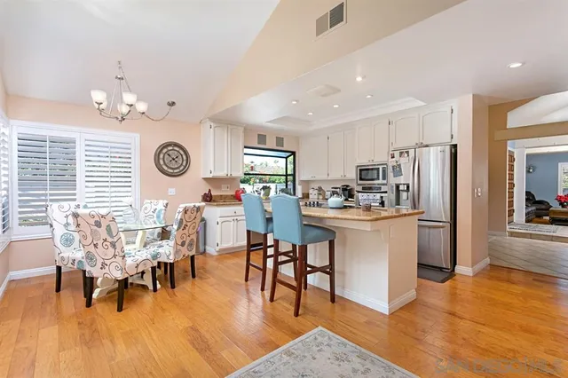 a kitchen with a dining table chairs and refrigerator
