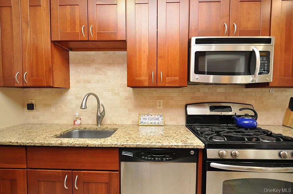 143 Garth Road, Unit 5J Scarsdale, NY 10583 - Photo 27 of 47 a kitchen with granite countertop stainless steel appliances wooden cabinets and a stove top oven
