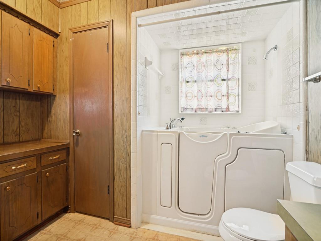 1081 Wright Street Terrell, TX 75160 - Photo 20 of 29 Bathroom featuring a walk-in tub with a shower fixture, white ceramic wall tile, and a window