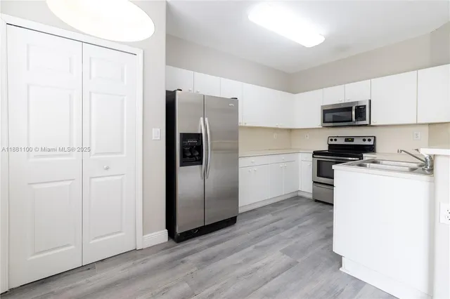 a kitchen with a refrigerator a microwave a sink and cabinets