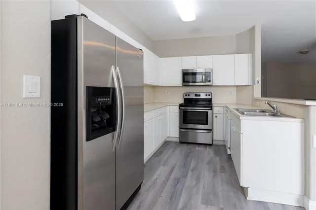 a kitchen with a refrigerator stainless steel appliances wooden floor and cabinets