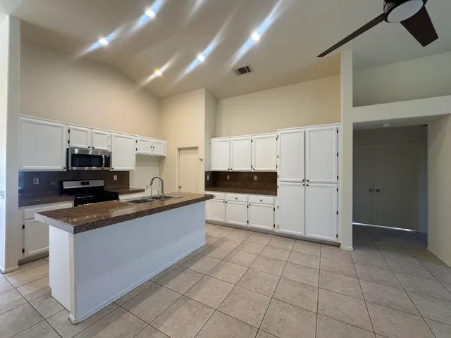 a kitchen with stainless steel appliances a sink a stove a microwave a sink a refrigerator and cabinets
