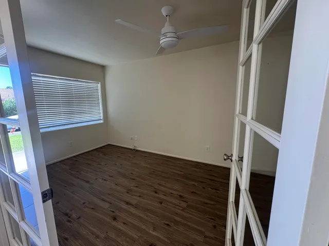 a view of an empty room with wooden floor and a window