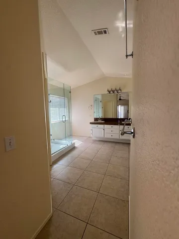 a view of a hallway with wooden floor and a bathroom