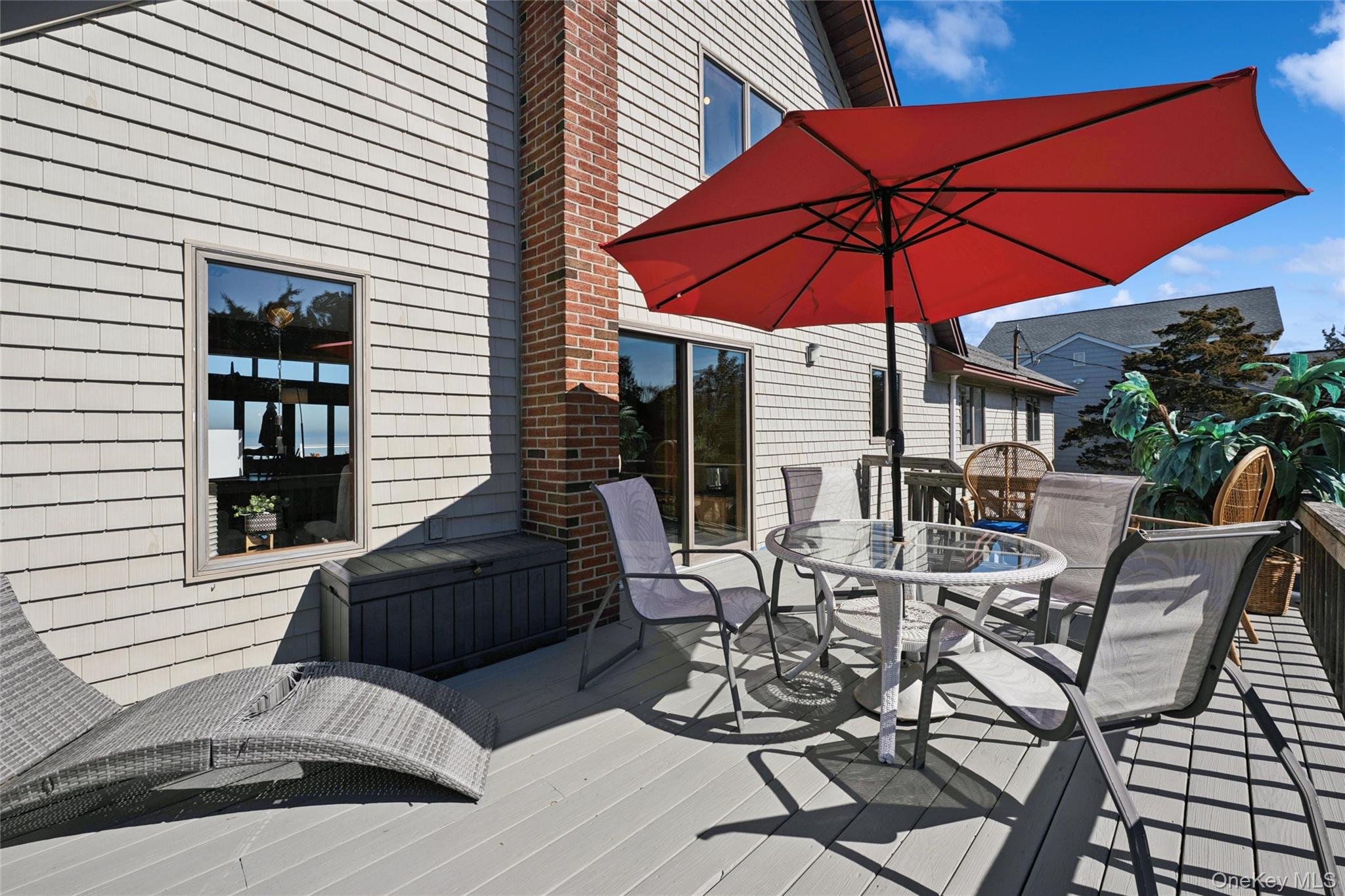 171 Harbor Beach Road Mount Sinai, NY 11766 - Photo 15 of 43 a view of a patio with couches table and chairs under an umbrella