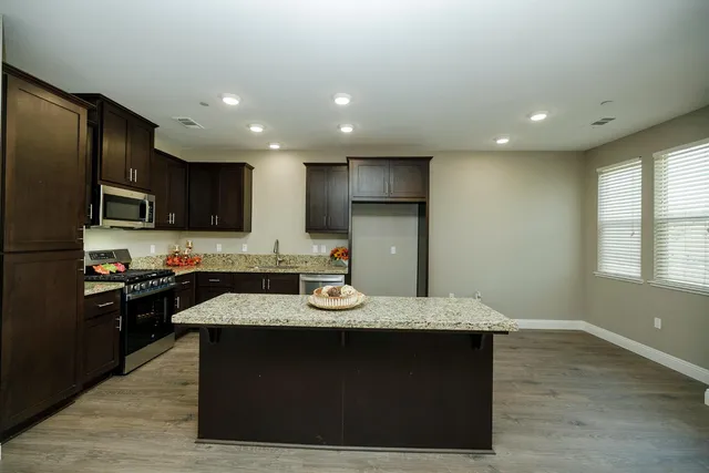 a kitchen with a sink a stove a refrigerator cabinets and a dining table