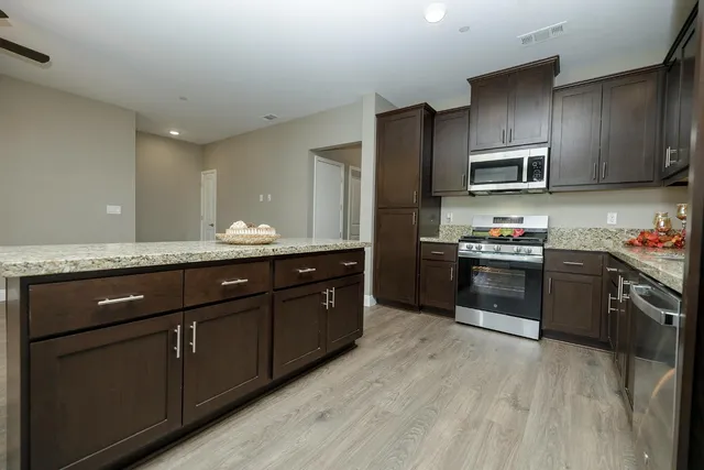 a kitchen with stainless steel appliances granite countertop a sink dishwasher stove and refrigerator