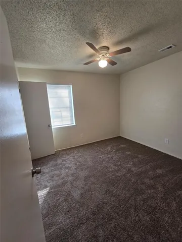 an empty room with windows and fan