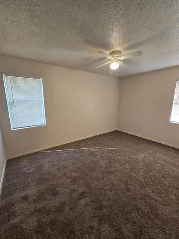an empty room with a window and ceiling fan