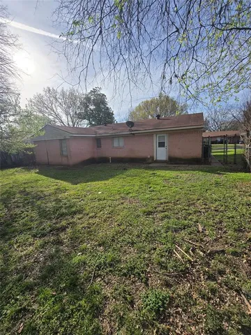 a view of house with yard and trees in the background