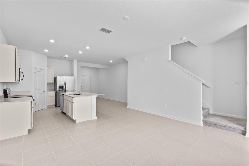 624 Poppy Lane Dundee, FL 33838 - Photo 2 of 23 a large white kitchen with kitchen island a stove a sink a refrigerator and white cabinets with wooden floor