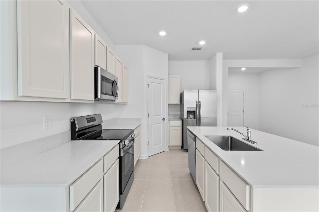 624 Poppy Lane Dundee, FL 33838 - Photo 5 of 23 a kitchen with stainless steel appliances granite countertop a sink a stove and a refrigerator