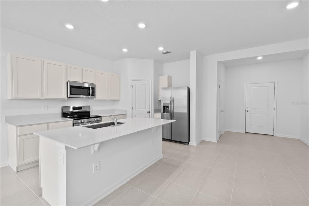 624 Poppy Lane Dundee, FL 33838 - Photo 6 of 23 a kitchen with stainless steel appliances granite countertop a refrigerator stove microwave and sink