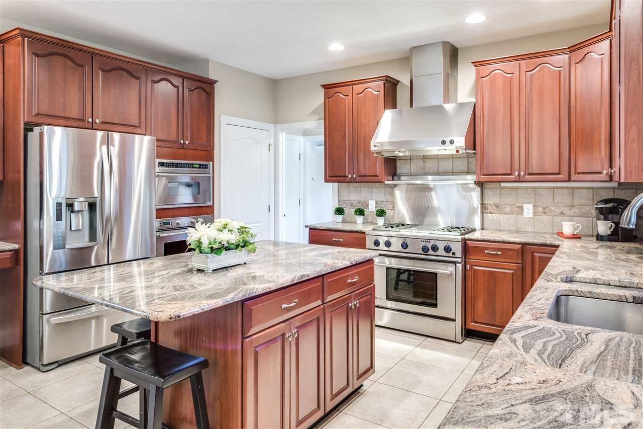 9004 Shellwood Court Raleigh, NC 27617 - Photo 9 of 25 a kitchen with kitchen island granite countertop a stove refrigerator and cabinets