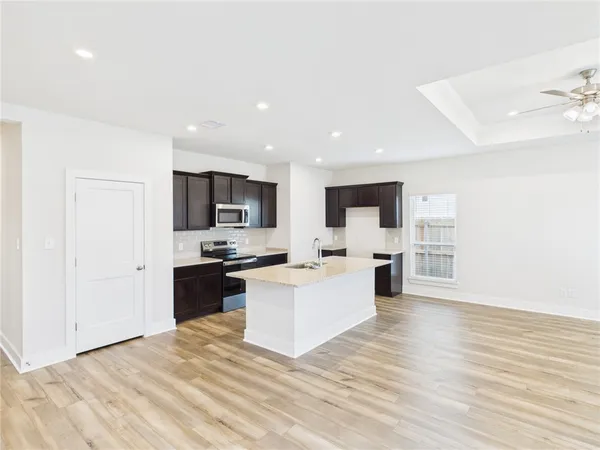 a view of kitchen with microwave stove refrigerator and cabinets