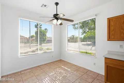 an empty room with a chandelier fan and windows