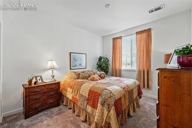 a bedroom with a bed and a lamp on dresser next to a window