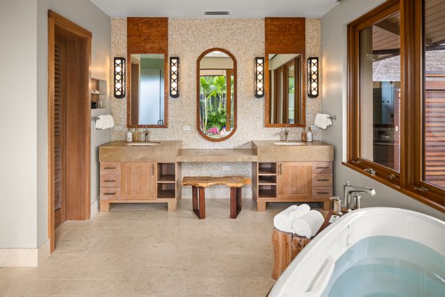 a bathroom with a granite countertop tub a double vanity sink and a large mirror