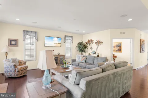 a view of a dining room and livingroom with furniture wooden floor a rug a painting and a chandelier