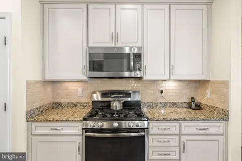 a kitchen with stainless steel appliances granite countertop a stove a sink and a refrigerator