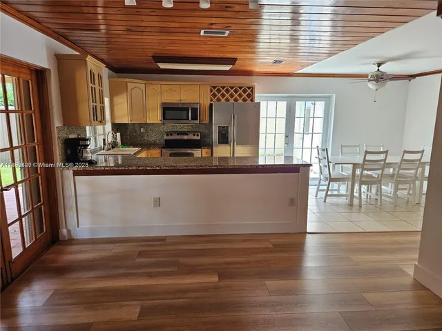 a view of a dining hall with stainless steel appliances granite countertop a stove and cabinets