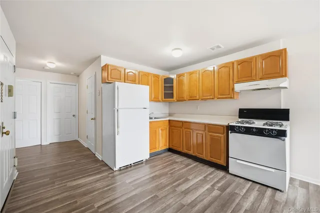 a kitchen with granite countertop wooden floors and white stainless steel appliances