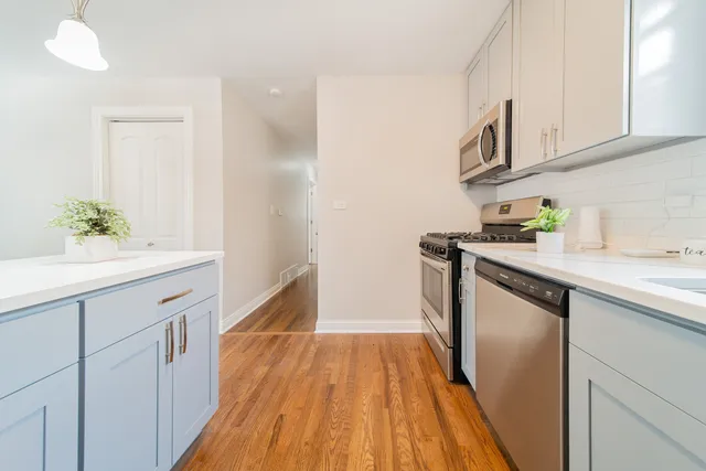 a kitchen with white cabinets and wooden floor