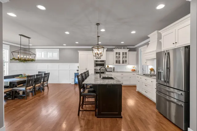 a kitchen with stainless steel appliances a dining table chairs stove and refrigerator