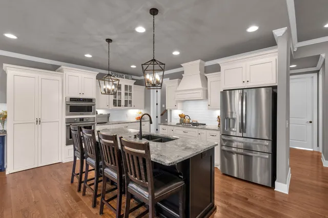 a kitchen with stainless steel appliances granite countertop a kitchen island a stove a table and chairs