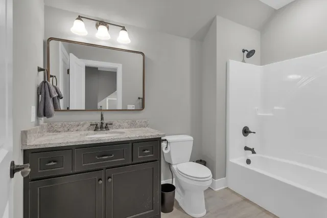 a bathroom with a granite countertop toilet sink and mirror