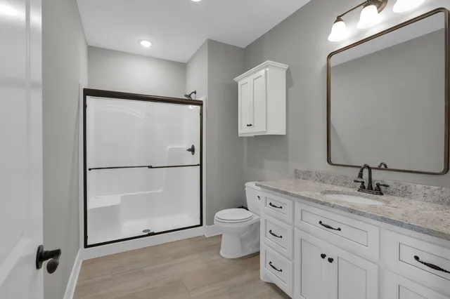 a bathroom with a granite countertop sink toilet and mirror