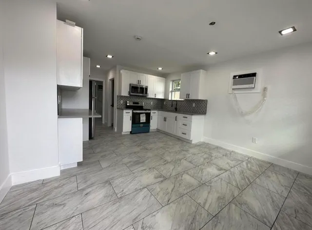 a large kitchen with a large counter top stainless steel appliances and cabinets