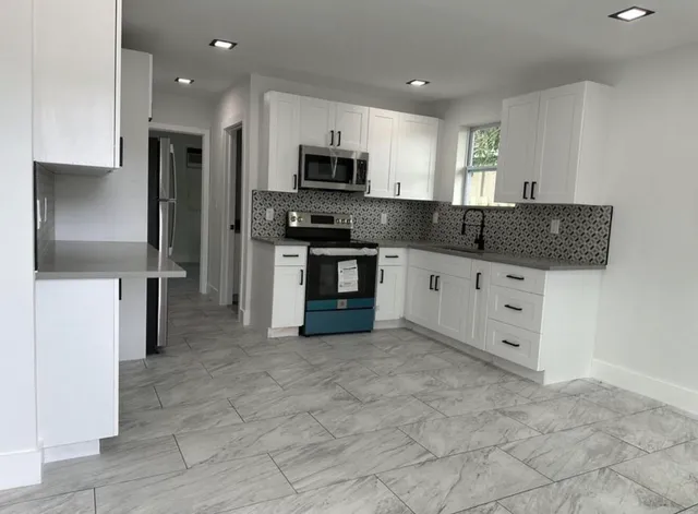 a kitchen with stainless steel appliances granite countertop a refrigerator and a stove top oven