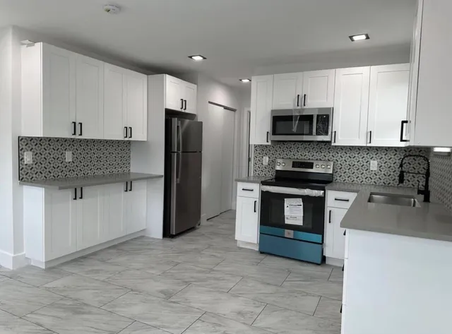 a kitchen with granite countertop a refrigerator and a stove top oven