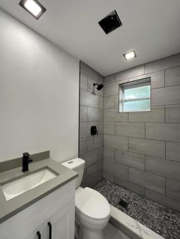 a bathroom with a granite countertop sink a toilet and shower