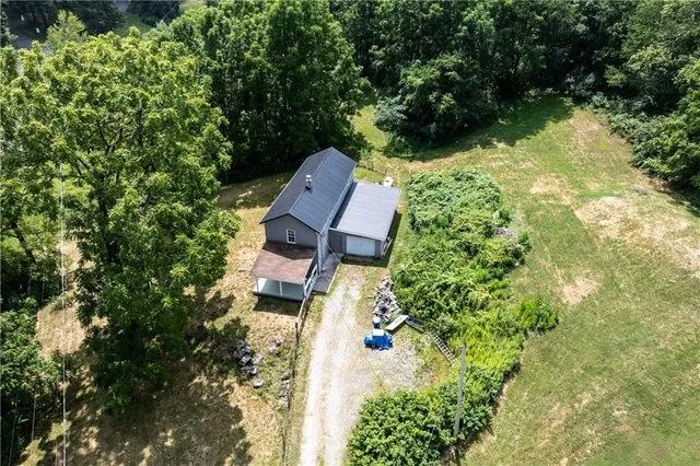 an aerial view of a house with garden space and trees all around