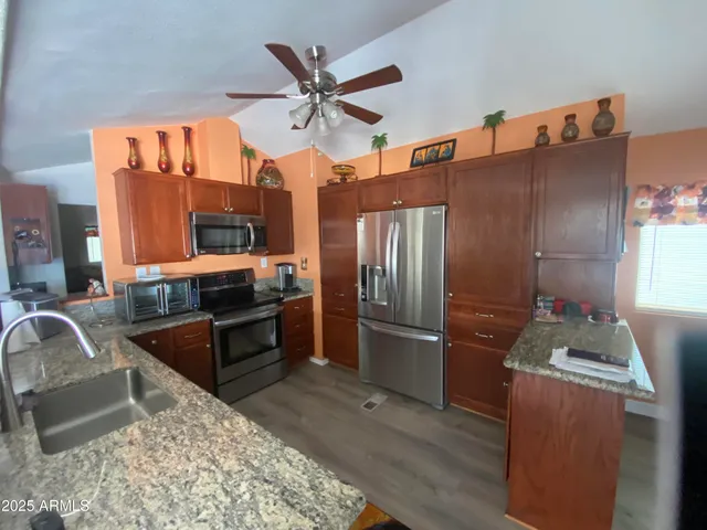 a kitchen with stainless steel appliances granite countertop a refrigerator a stove and a sink