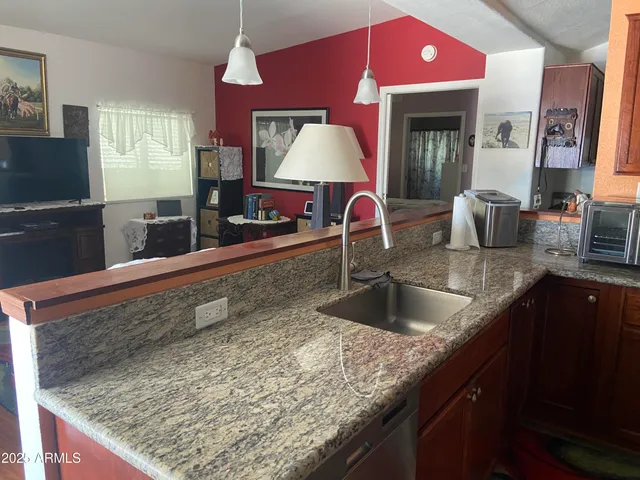 a kitchen with granite countertop a sink a counter top space and cabinets
