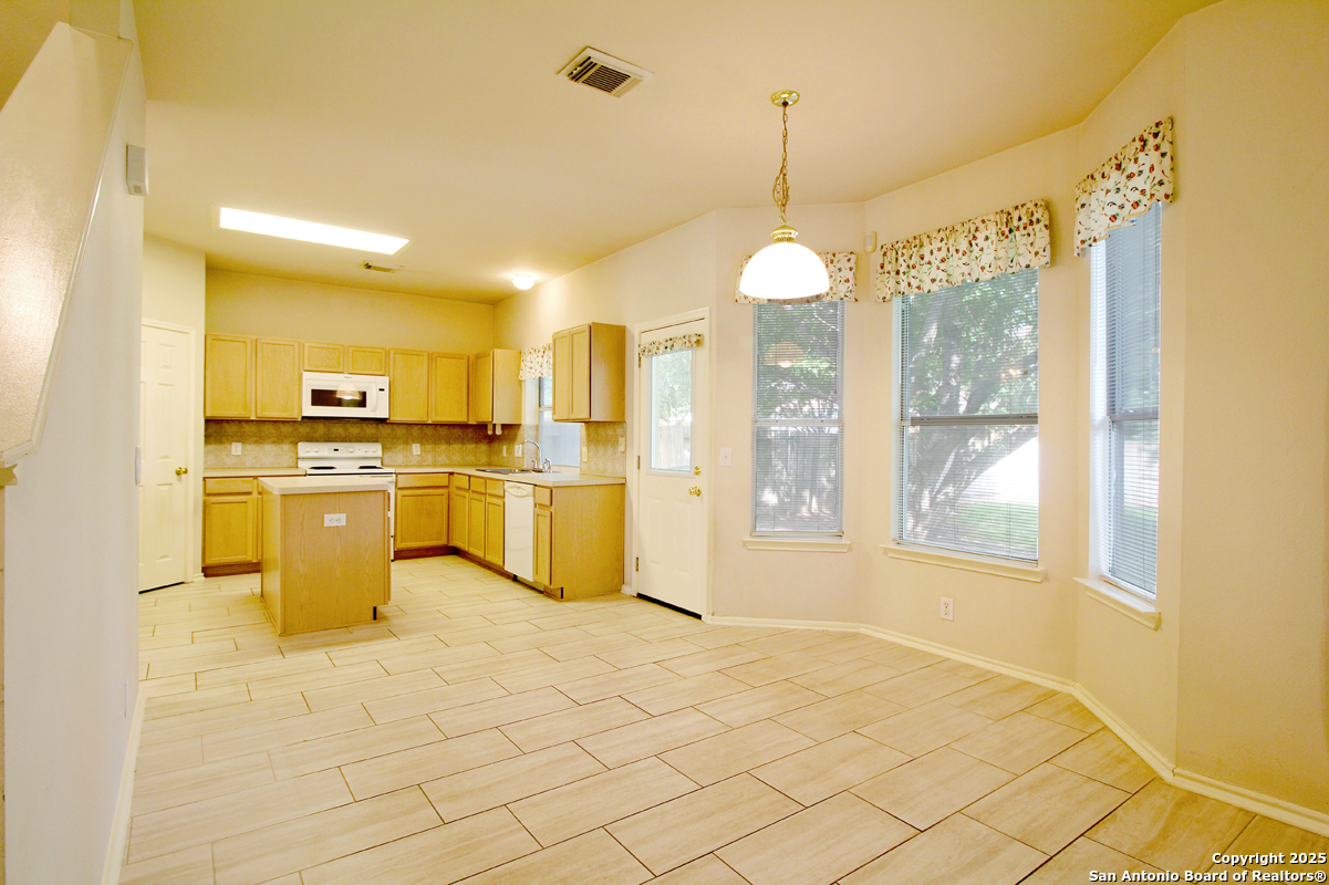 2703 Rio Brazos San Antonio, TX 78259 - Photo 12 of 34 a kitchen that has a lot of white cabinets and a chandelier