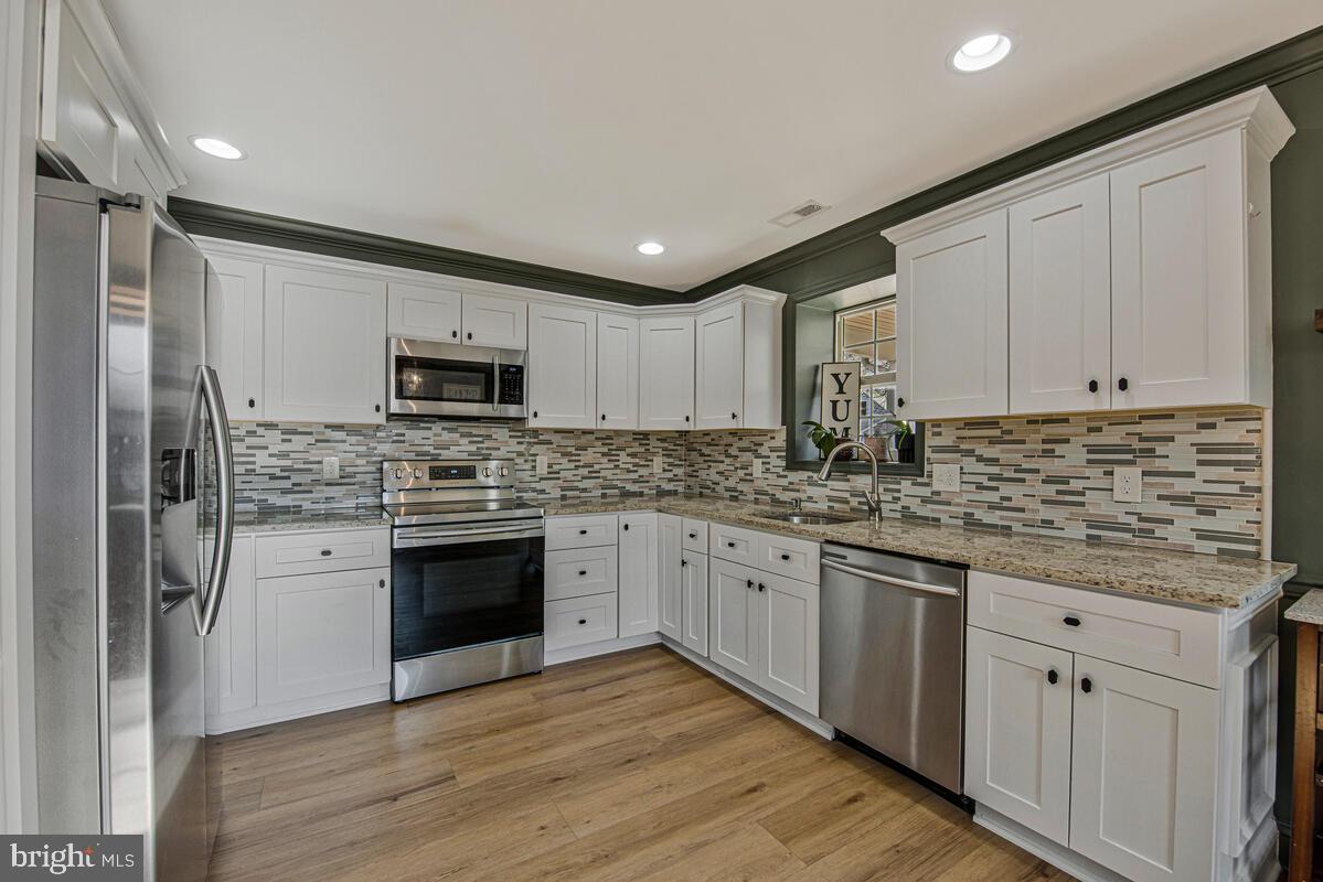 941 8th Street Pasadena, MD 21122 - Photo 10 of 41 a kitchen with stainless steel appliances granite countertop a stove top oven a sink and dishwasher with wooden floor