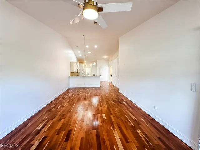 a view of an empty room with window and wooden floor