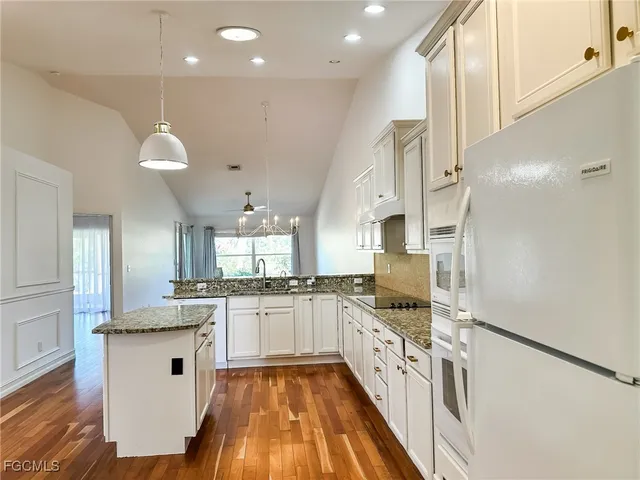a kitchen with stainless steel appliances granite countertop a stove a sink and white cabinets with wooden floor