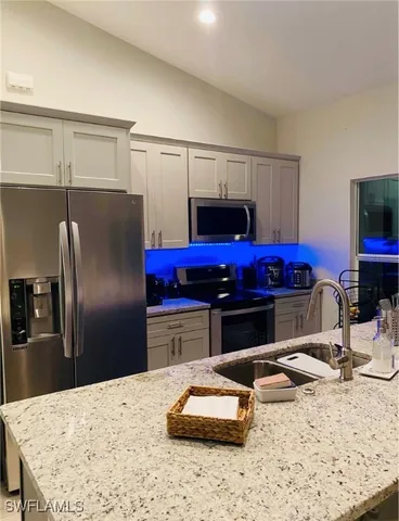 a kitchen with stainless steel appliances kitchen island granite countertop a refrigerator a stove and a sink