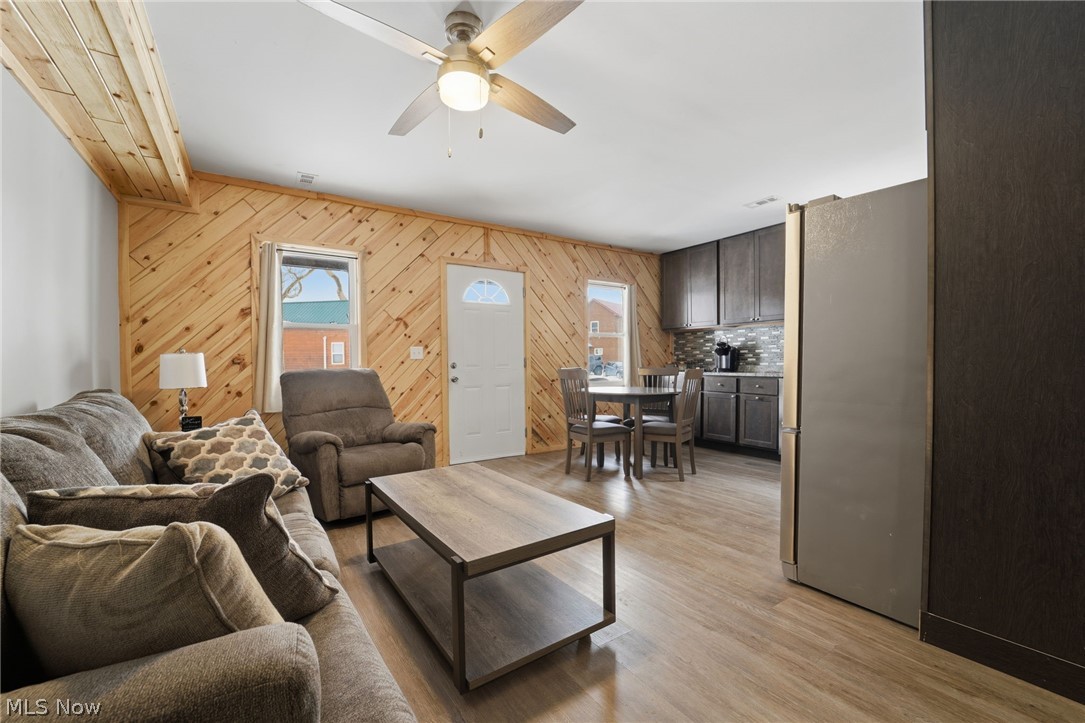 5919 Lake Road West, Unit 33 Ashtabula, OH 44004 - Photo 5 of 22 Living area featuring a ceiling fan, light wood-type flooring, and wood walls