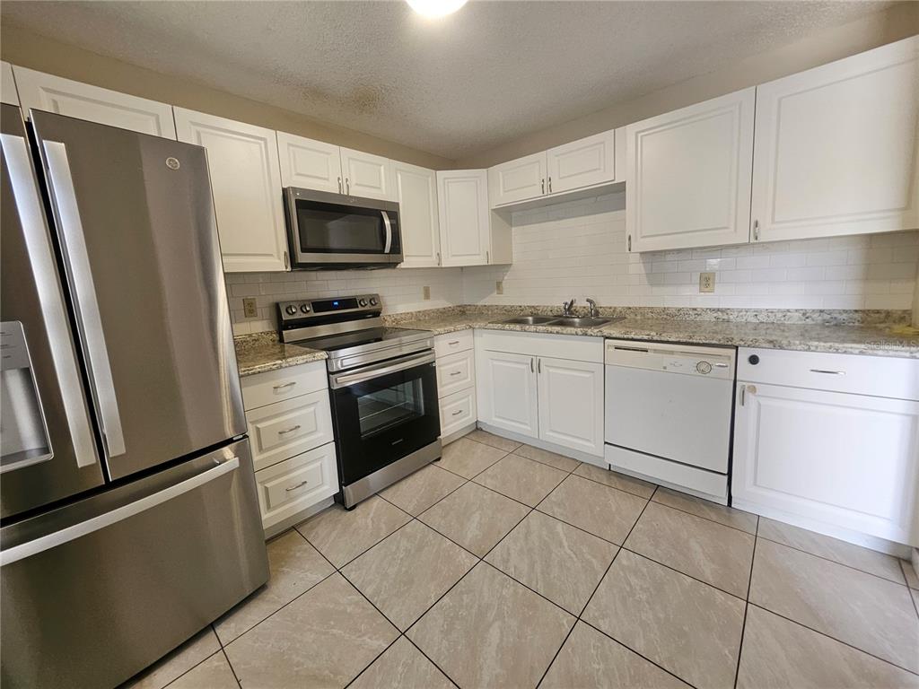 1612 Sandy Point Square, Unit 56 Orlando, FL 32807 - Photo 7 of 26 a kitchen with white cabinets stainless steel appliances and a sink