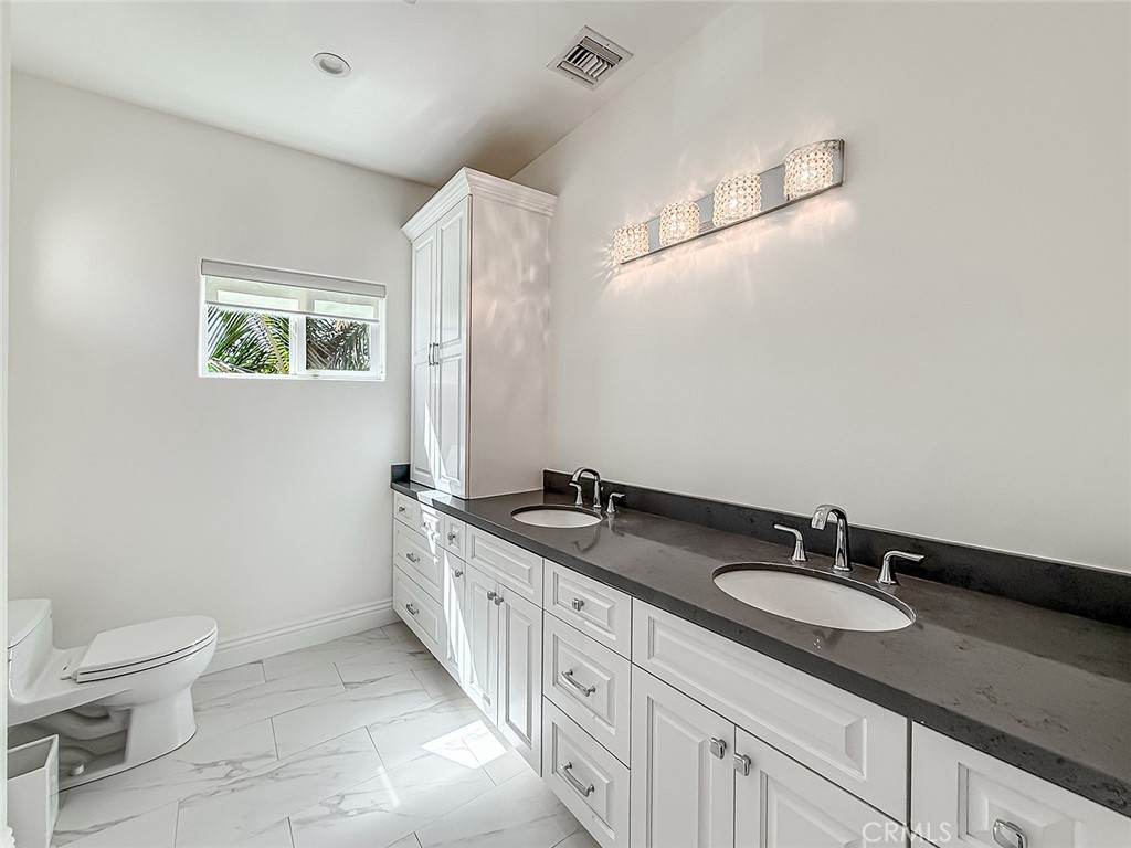 5960 Balcom Avenue Encino, CA 91316 - Photo 47 of 58 a bathroom with a granite countertop sink a toilet a mirror and shower