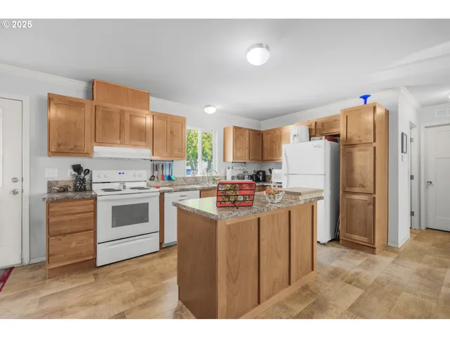 a kitchen with a refrigerator a stove top oven a sink dishwasher and white cabinets with wooden floor