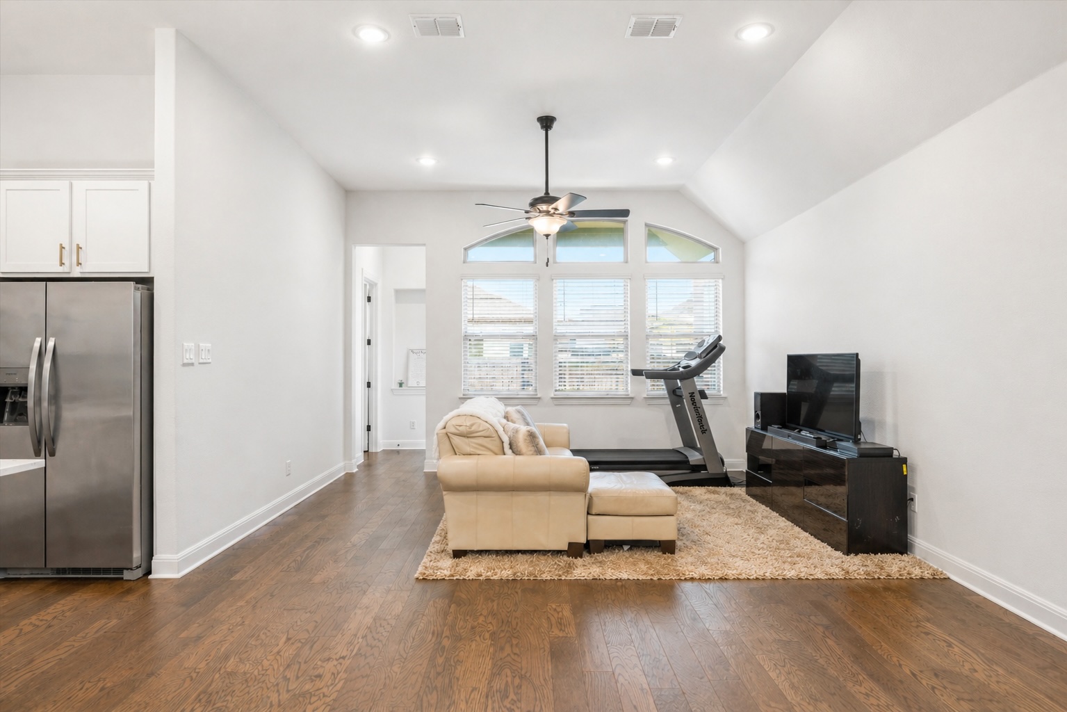 209 Rainier Drive Kyle, TX 78640 - Photo 20 of 24 Open-concept living space with wood-finish flooring, vaulted ceilings, recessed lighting, and an arched window bank